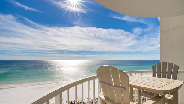 A balcony with a view of the ocean, a table, and two chairs. - 2BR Beachfront Condo at Hidden Dunes! Beach Views, 3 Tropical Pools, Hot Tub. (Miramar Beach)