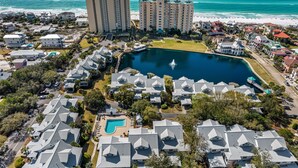 An aerial view of a coastal resort with multiple buildings, a central pool, and a beach in the background. - 2BR Beachfront Condo at Hidden Dunes! Beach Views, 3 Tropical Pools, Hot Tub. (Miramar Beach)