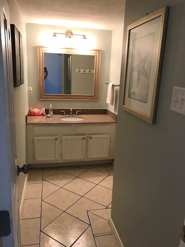 Casa de banho com lavatório, espelho e chão em azulejo.