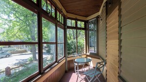 Une véranda avec de grandes fenêtres, une table et des chaises.