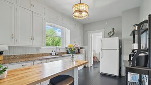 Une cuisine moderne avec des armoires blanches, un plan de travail en bois et un tabouret de bar noir.