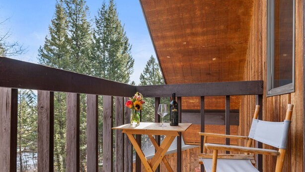 A wooden deck with a table and a chair, a bottle of wine, and a glass on the table. - RMR: Stock House in Teton Village (Teton Village)