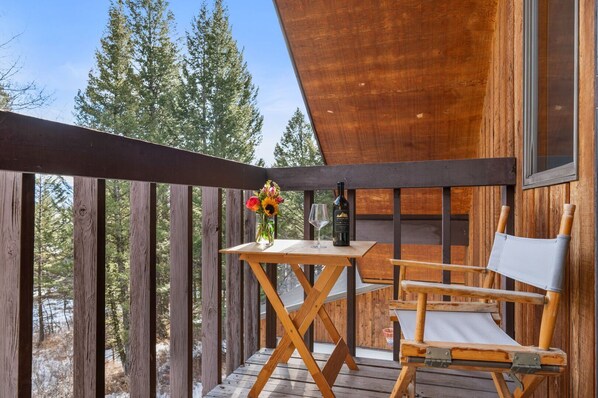 A wooden deck with a table and a chair, a bottle of wine, and a glass on the table. - RMR: Stock House in Teton Village (Teton Village)