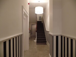 Staircase leads to an upper level, with a door and radiator visible.