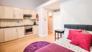 Eine moderne Küche mit hellen Holzschränken, einem eingebauten Backofen und einer schwarzen Arbeitsplatte.
