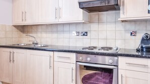 Eine Küche mit hellen Holzschränken, einem Edelstahlherd und einem eingebauten Backofen.
