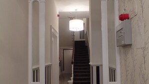 Ein Flur mit Treppe, weißen Wänden und einer Kristallleuchter.