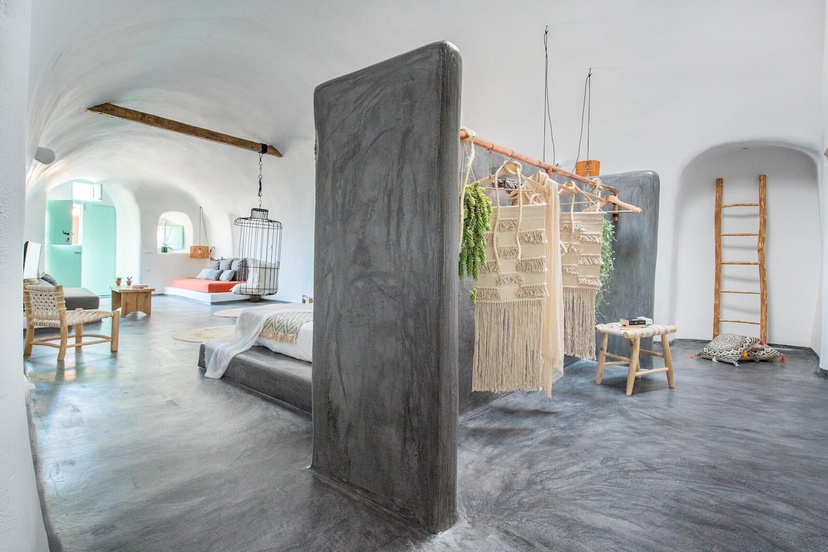 A spacious room with a high ceiling, a large central column, and a hanging macrame wall hanging.