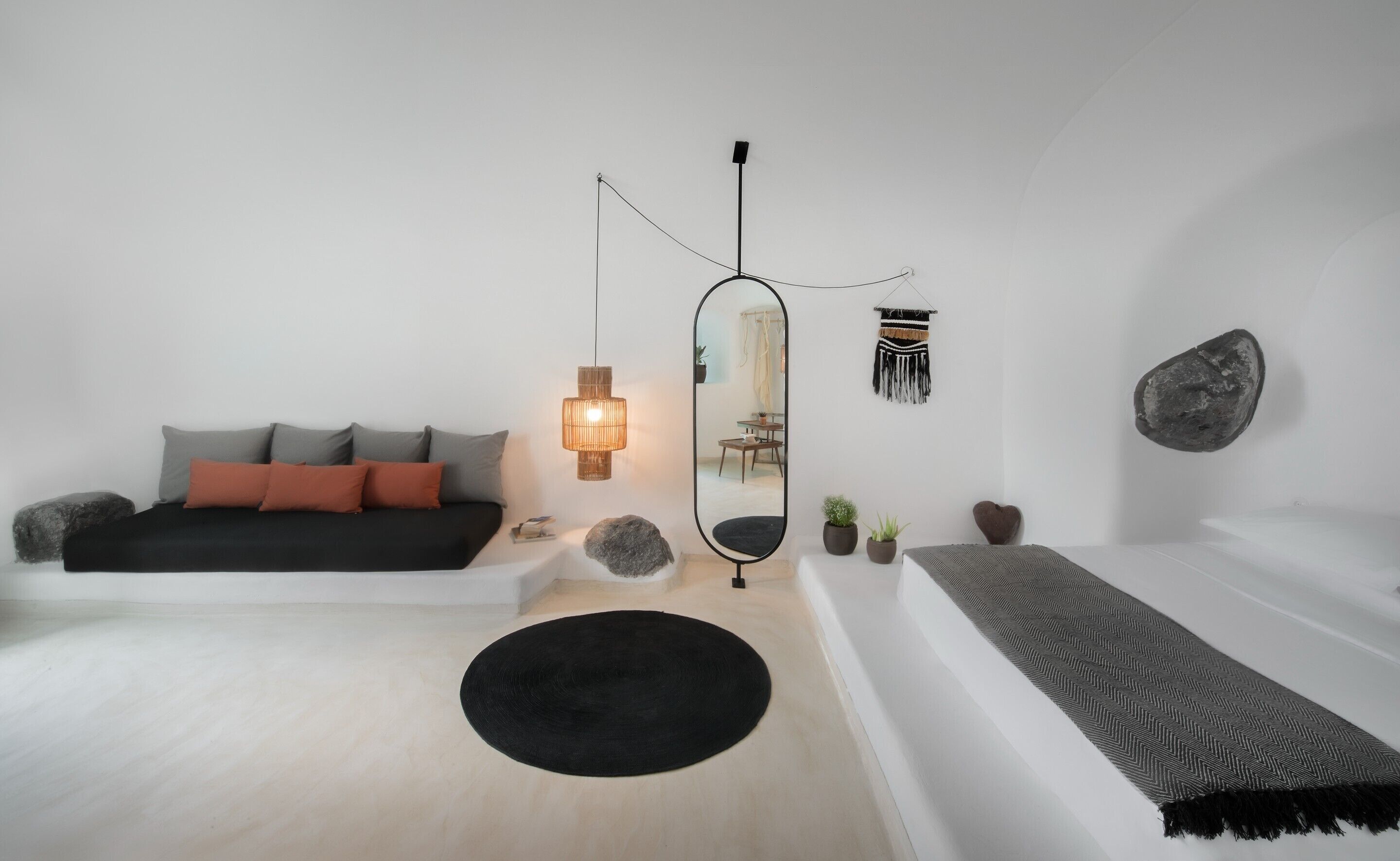 A modern bedroom with a bed, a round mirror, a hanging light, and a wall-mounted decorative piece.
