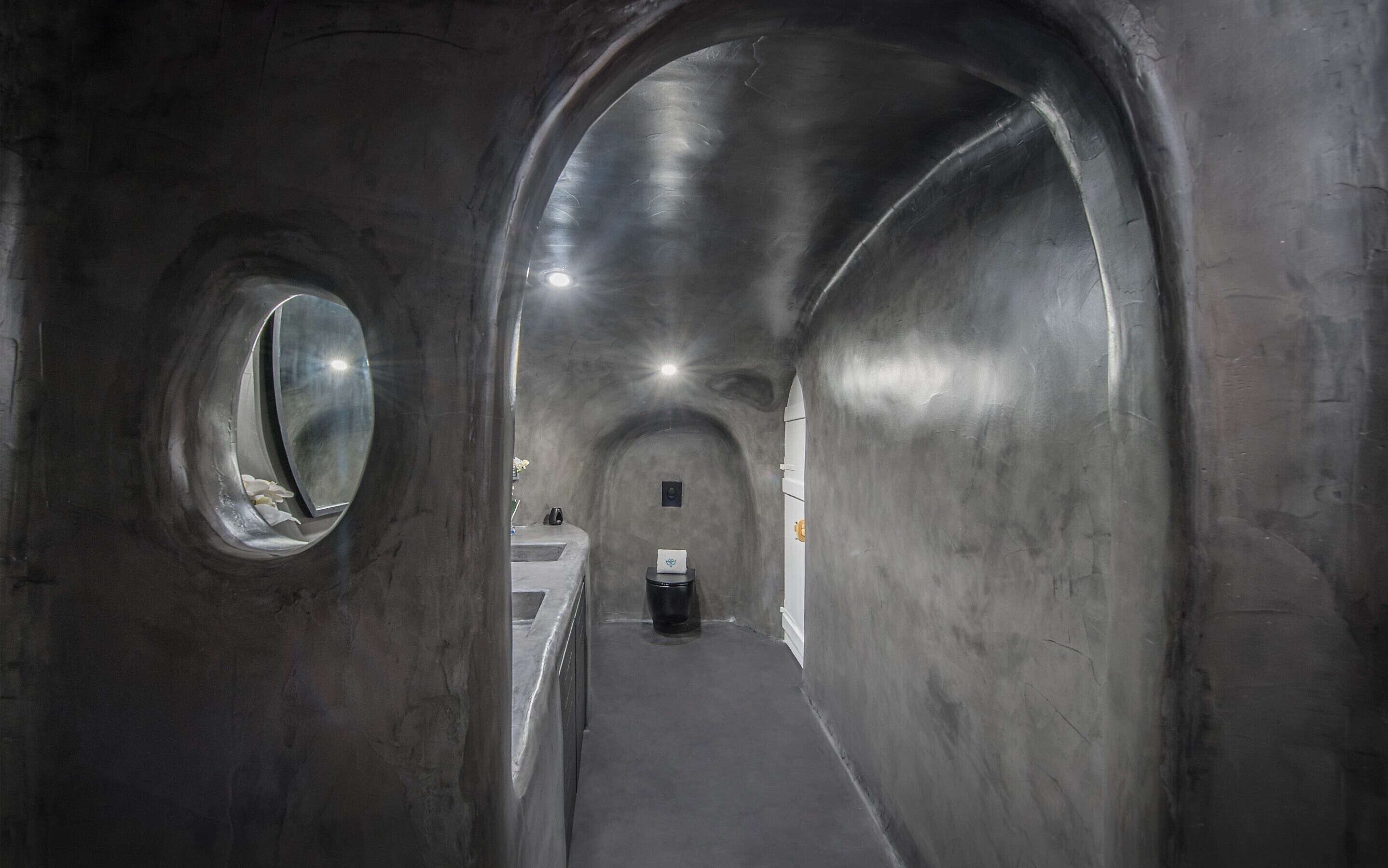 En tunnelformad korridor med välvda tak och runda fönster.