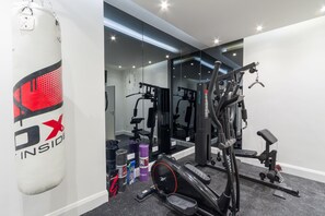 A gym with exercise equipment, a punching bag, and a mirror reflecting the room.