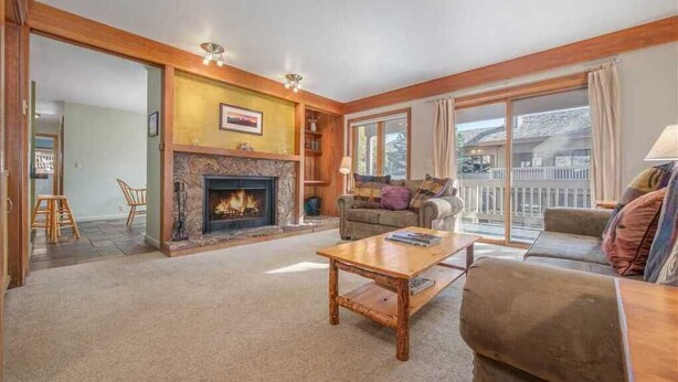 A cozy living room with a fireplace, a sofa, a coffee table, and a view of the outside. - RMR: Teewinot A2 Condo in Teton Village (Teton Village)