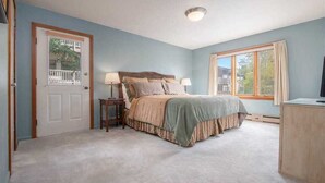 A bedroom with a bed, two bedside tables, a window, and a door. - RMR: Teewinot A2 Condo in Teton Village (Teton Village)