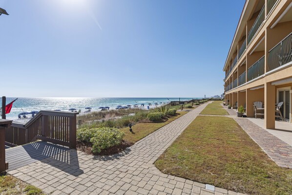 A hotel with a beachfront view, a paved walkway, and outdoor seating areas.