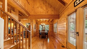 A wooden cabin interior with a dining area, staircase, and large windows. - Large Cabin Near Downtown Blowing Rock (Blowing Rock)