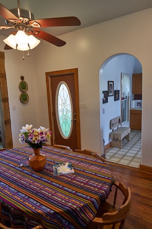 Enjoy meals in this cozy dining area with a table for two, a vase with flowers, and a welcoming bench.