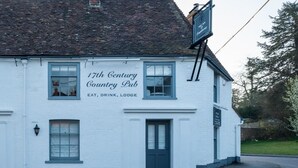 Um edifício branco com uma placa que diz 'Pub Campestre do Século XVII' e 'COMIDA, BEBIDA, HOSPEDAGEM'.