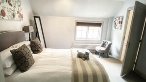 Quarto com uma cama grande, uma escrivaninha e um radiador.
