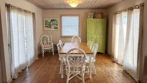 Comedor con una mesa y sillas de madera, un armario verde y una ventana con persianas.