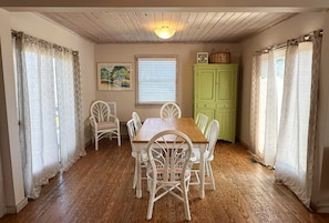 A dining room with a wooden table and chairs, a green cabinet, and a window with blinds.