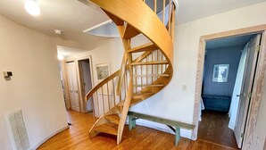 Una escalera de caracol en un pasillo con suelo de madera y paredes blancas.