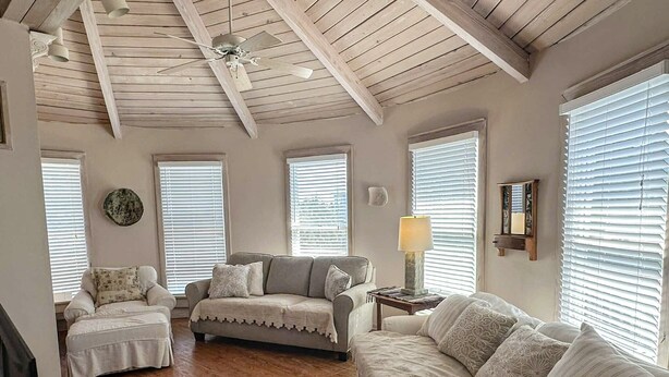 Una sala de estar acogedora con techo de madera, un conjunto de sofá, una mesita de centro y una lámpara.