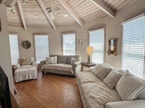 A cozy living room with a wooden ceiling, a sofa set, a coffee table, and a lamp. - Moondance:  Comfortable, true relaxation, soothing colors and décor. (Ocracoke)