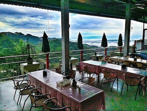 An outdoor dining area with tables and chairs, umbrellas, and a view of the mountains. - King Villa (Taichung)