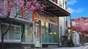 Un edificio japonés tradicional con escaparate, ventanas amplias y flores de cerezo.