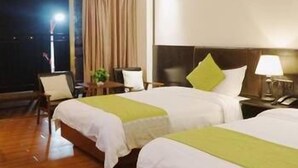 A hotel room with two beds, a nightstand with a lamp, a chair, and a window with curtains. - Mingju Holiday Hotel (Yangjiang)