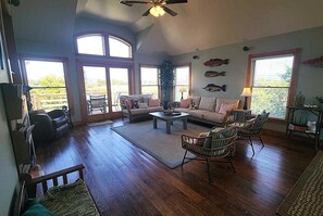 Ein geräumiges Wohnzimmer mit großem Fenster, Deckenventilator und einer Couch.