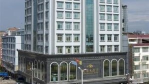 A multi-story hotel with a central glass elevator shaft, large windows, and a symmetrical facade.
