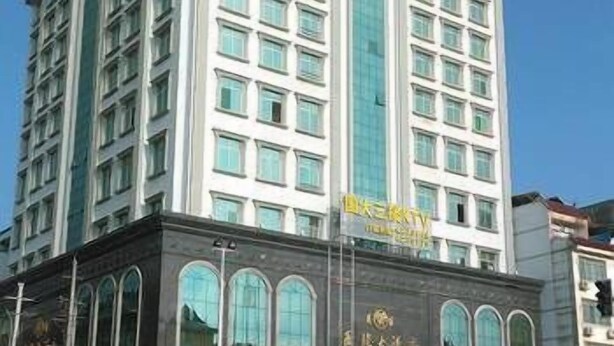 A multi-story hotel with a central vertical glass facade, multiple balconies, and a traditional architectural style.