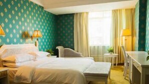 A hotel room with a bed, a desk, a chair, and a small table.