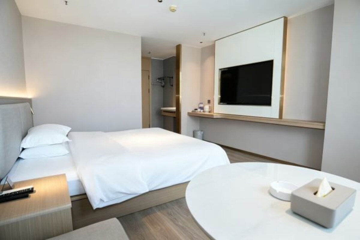 Habitació d'hotel amb llit, taula de nit, televisió i una taula rodona amb una caixa de mocadors.