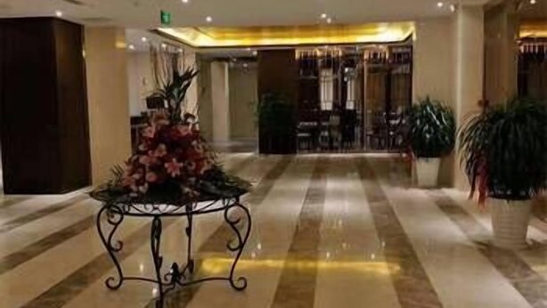 A hotel lobby with a marble floor, a decorative table with flowers, and potted plants. - Jinjiang Jinqiao Hotel (Liangshan Yi)