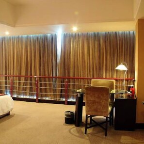 A hotel room with a bed, a desk, a chair, a lamp, and a large window with curtains. - Jinjiang Jinqiao Hotel (Liangshan Yi)