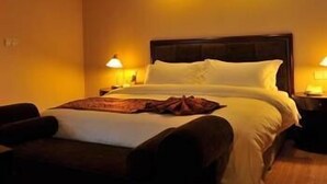 A hotel room with a large bed, two bedside lamps, and a wooden headboard. - Jinjiang Jinqiao Hotel (Liangshan Yi)