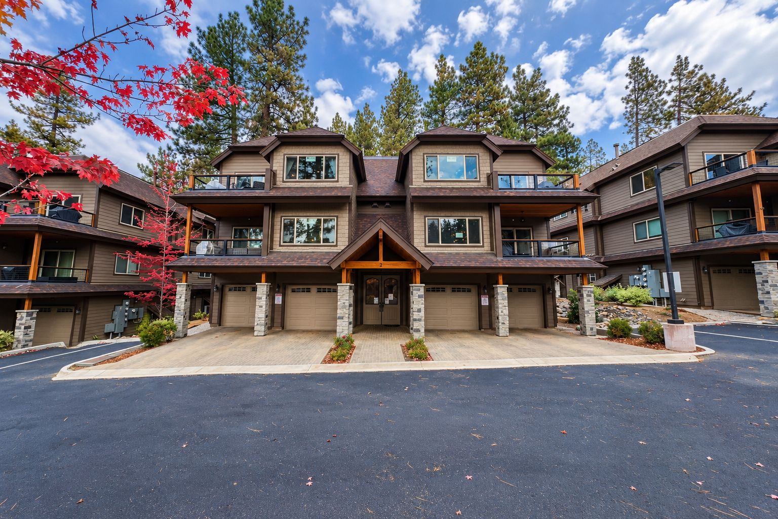 A multi-story residential building with a central entrance, multiple balconies, and a driveway.
