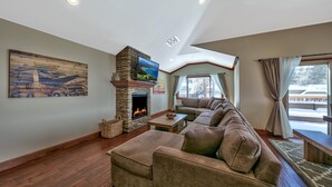 Una sala de estar con chimenea de piedra, un sofá grande y un televisor.