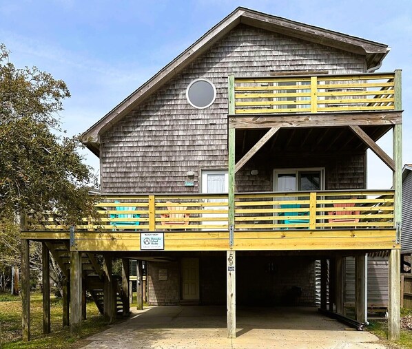 Un bâtiment en bois à deux étages, doté d’un balcon, d’une fenêtre circulaire et d’une porte.