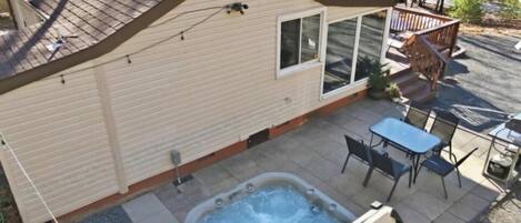 A small cabin with a hot tub, patio seating, and a deck.
