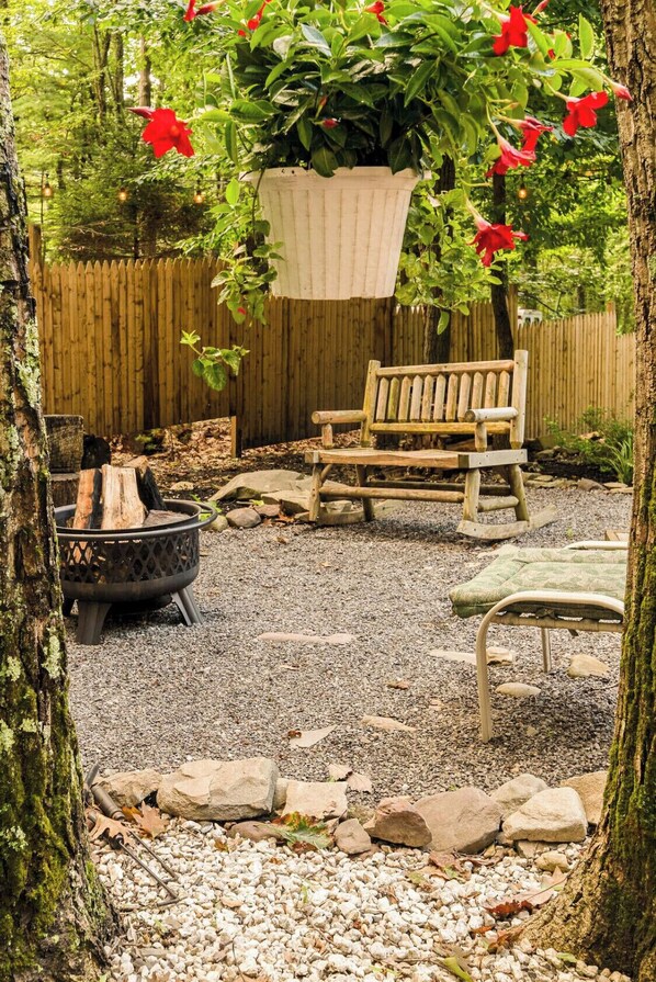 Relax in a serene garden setting with a cozy bench and fire pit, surrounded by natural elements and lush greenery.