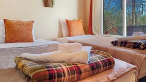 Une chambre d’hôtel avec deux lits, une fenêtre donnant sur la verdure et un panier de fleurs accroché au mur.