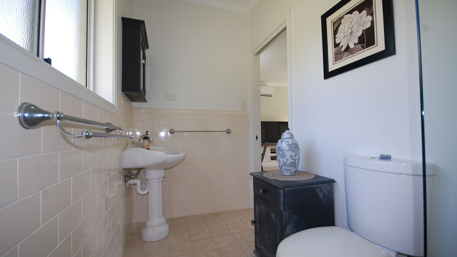 A bathroom with a white sink, a toilet, and a small cabinet.