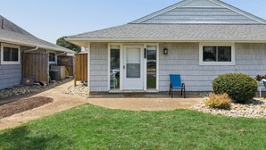 A single-story house with a front porch, a small garden area, and a blue chair. - Full Condo w/ pool, 5 min walk to beach (Virginia Beach)