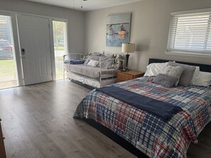A bedroom with a bed, a chair, a nightstand, a lamp, and a painting on the wall. - Full Condo w/ pool, 5 min walk to beach (Virginia Beach)