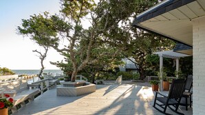Eine Holzterrasse mit Sitzgelegenheiten im Freien, einer Pergola und Meerblick.