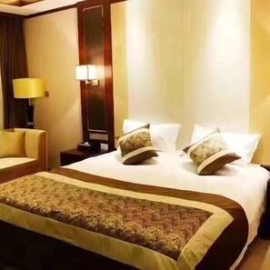 Ein Hotelzimmer mit einem großen Bett, einem Nachttisch, einer Lampe und einem Sessel.