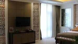 Ein Hotelzimmer mit einem großen Bett, einem Fernseher auf einem Schrank und einem Vorhangfenster.